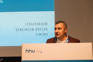 Bulut Surat vom DGB NRW steht am Rednerpult und spricht.