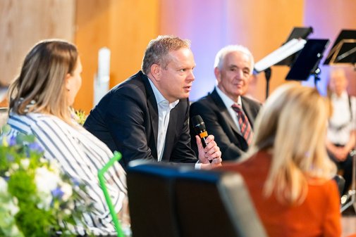 Johannes Pöttering sitzt in der Diskussionsrunde auf der Bühne und spricht in ein Mikrofon. 