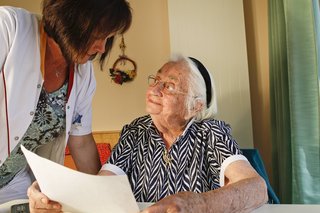 Eine Heimbetreuerin erklärt einer alten Frau ein Dokument