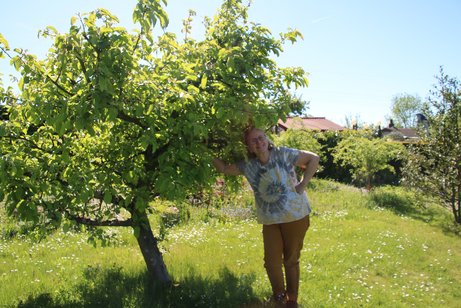 Gudrun Rudolph lehnt l&auml;chelnd an ihrem Apfelbaum