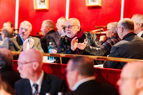 Viele Menschen sitzen an Tischen verteilt in eine Saal. 