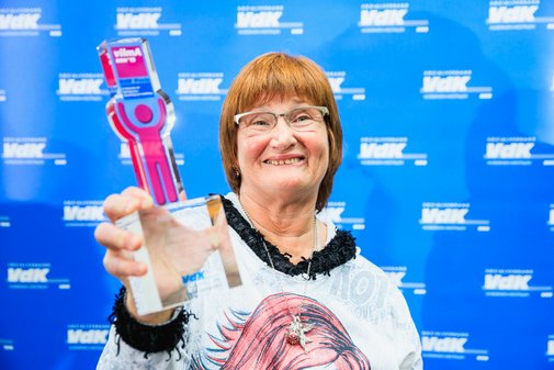 Eine Gewinnerin hält den vilmA-Pokal lächelnd in Richtung Kamera. 