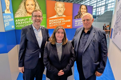 Von links nach rechts: Thomas Zander, Manuela Dörtelmann, Karl-Josef-Laumann. Im Hintergrund der VdK-Messestand mit Slogan: Menschenwürdige Pflege sicherstellen.