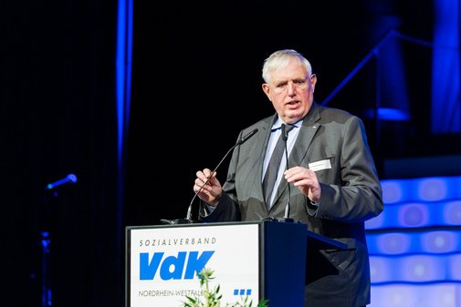 Minister Laumann steht an einem Pult auf der B&uuml;hne. Das Pult hat ein Schild mit der Aufschrift VdK.