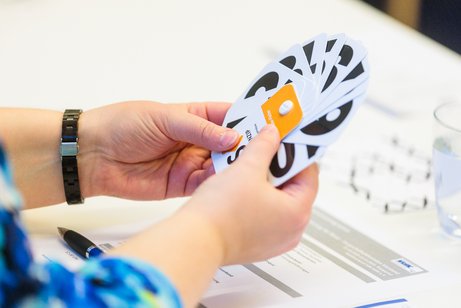 Frau hält Kartenfächer mit verschiedenen Zahlen in der Hand.