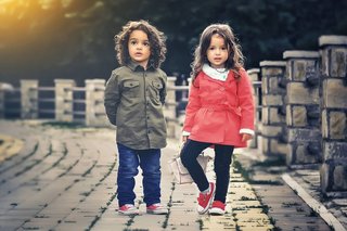 Ein Junge und ein Mädchen stehen nebeneinander auf einem gepflasterten Weg