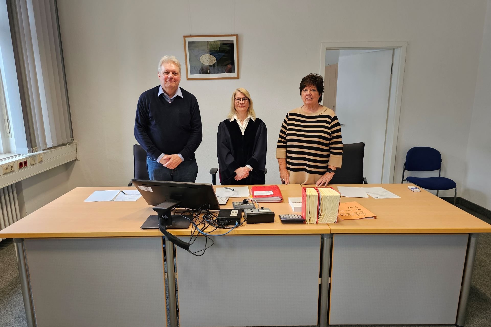 Gruppenfoto dreier Richter und Richterinnen hinter einem großen Schreibtisch.