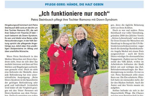 Ausschnitt einer Zeitungsseite mit einem Bild von zwei Frauen, eine davon mit Down Syndrom, die beide eine Hand mit Daumen hoch zeigen.