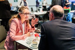 Grünen-NRW-Ministerin Antje Grothus sitzt an einem Tisch im Gespräch mit einem weiteren Gast.