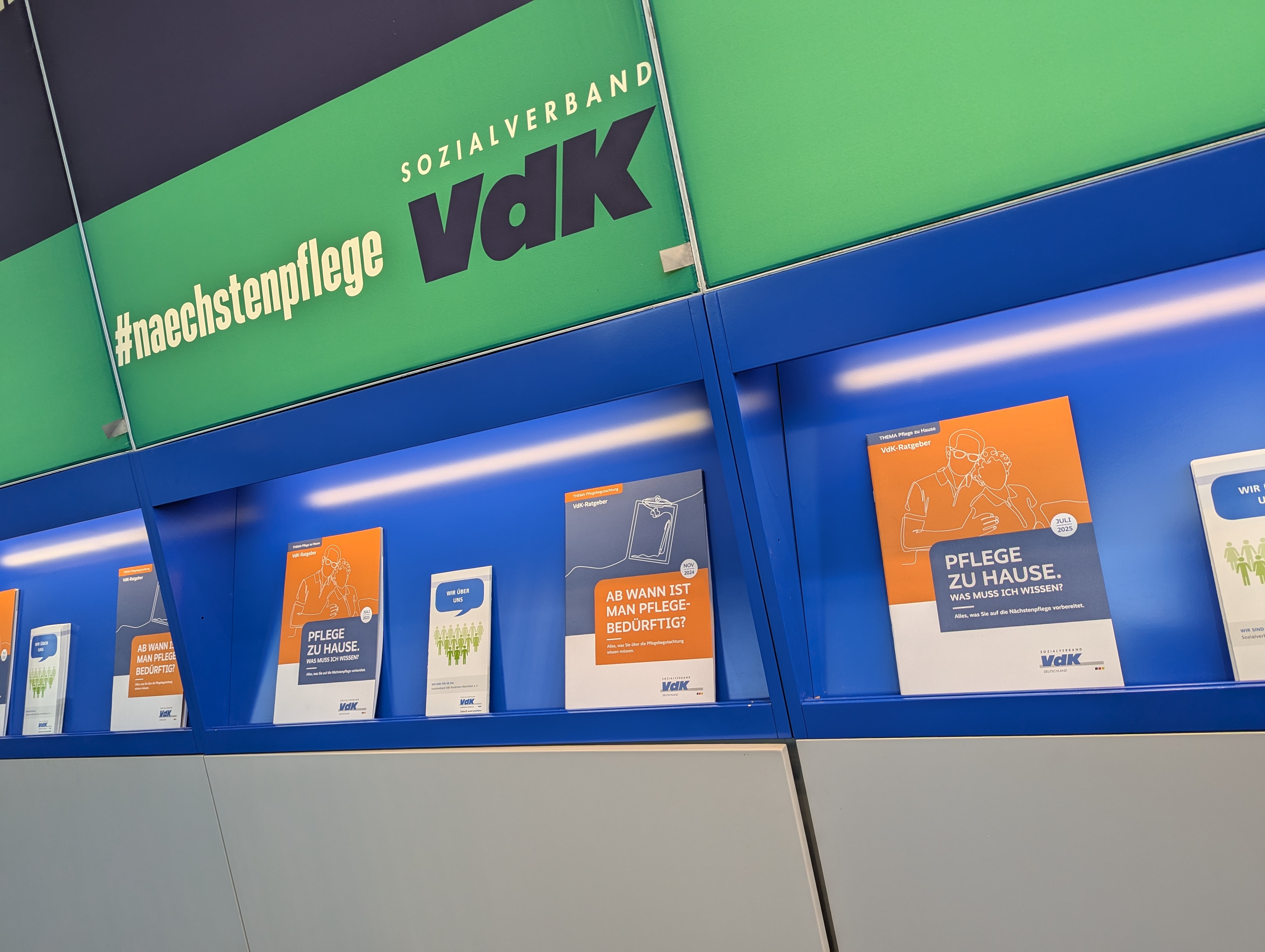 Pflegebroschüren am VdK-Messestand. Darüber der Slogan: Nächstenpflege jetzt!
