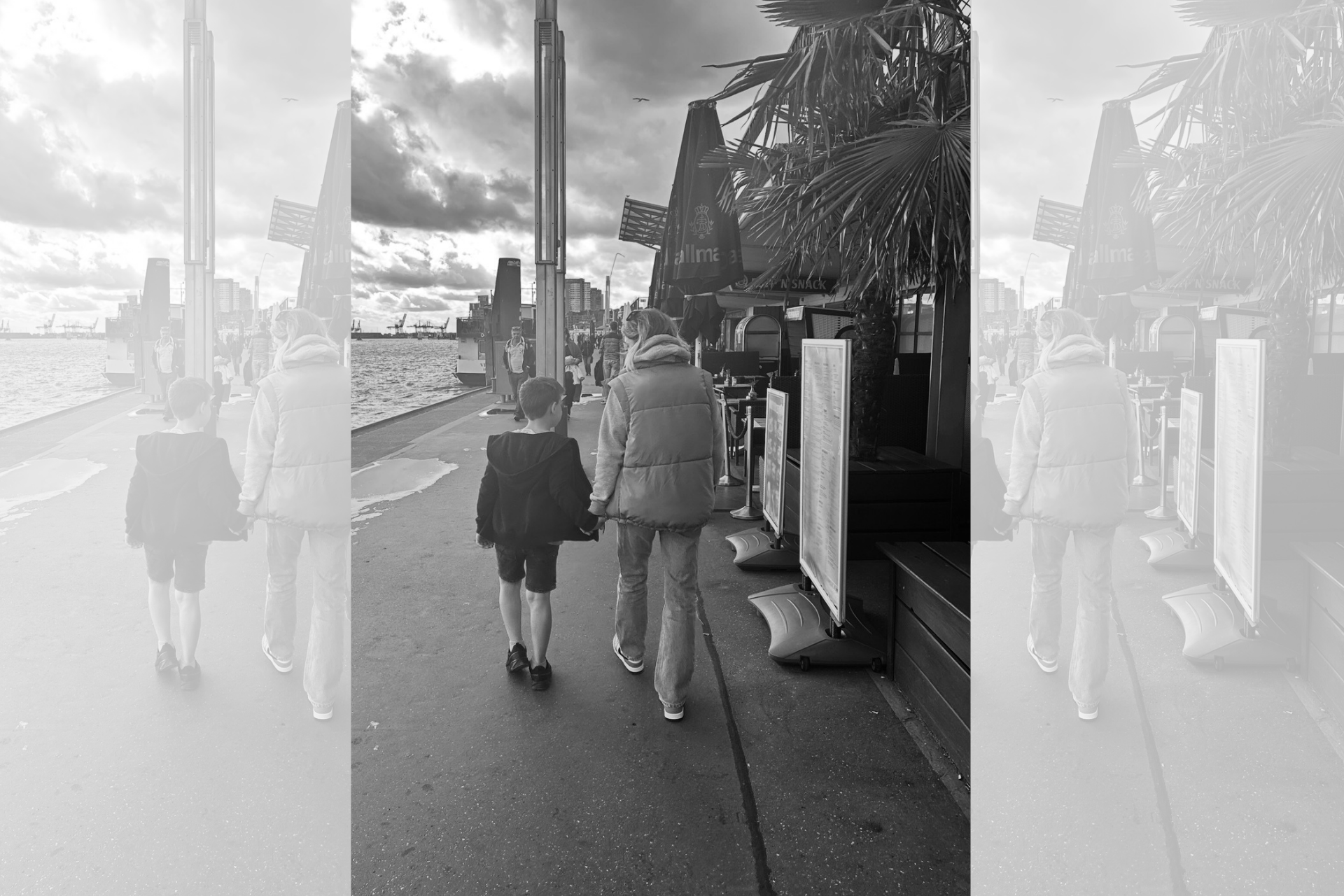 Schwarzwei&szlig;bild von Mutter und Sohn, die eine Promenade entlanglaufen.
