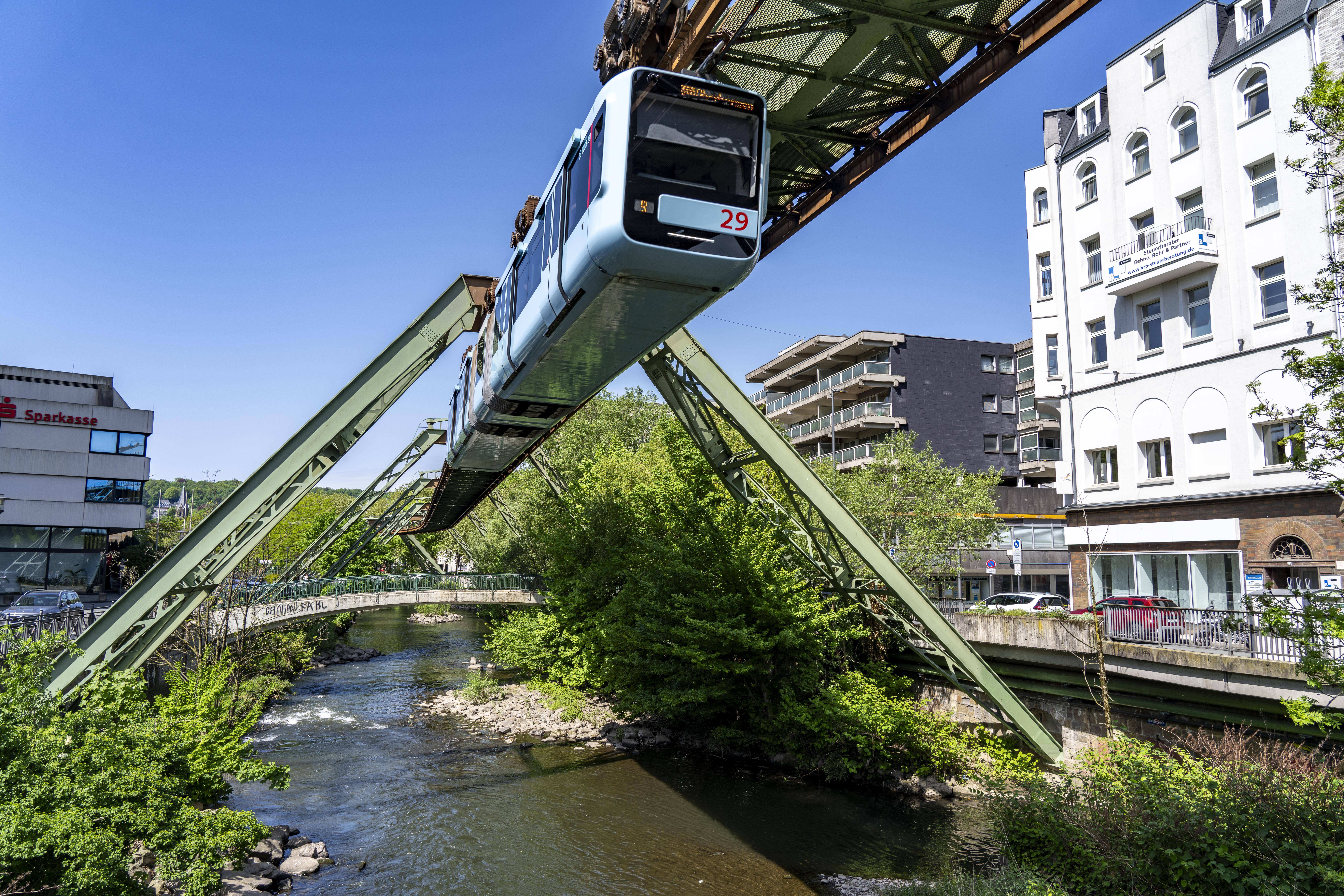 Ein Wagen der Wuppertaler Schwebebahn f&auml;hrt &uuml;ber der Wupper entlang des Gleisger&uuml;sts..