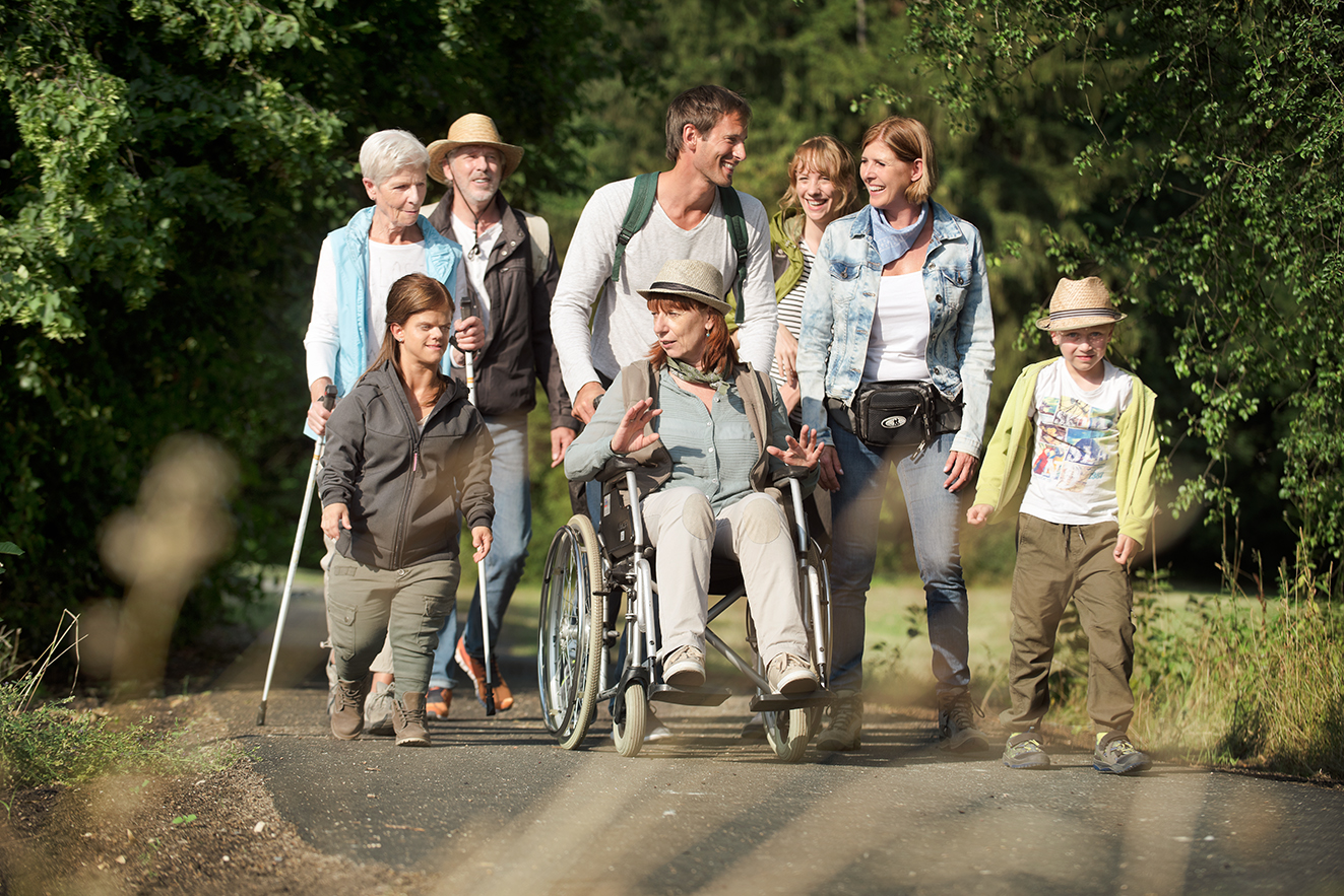 VdK-Ausflug - gemeinsam unterwegs Eine Gruppe von VdK-Mitgliedern - Männer und Frauen, mit und ohne Behinderung - ist gemeinsam draußen unterwegs wie bei einer Wanderung. Sie unterhalten sich.