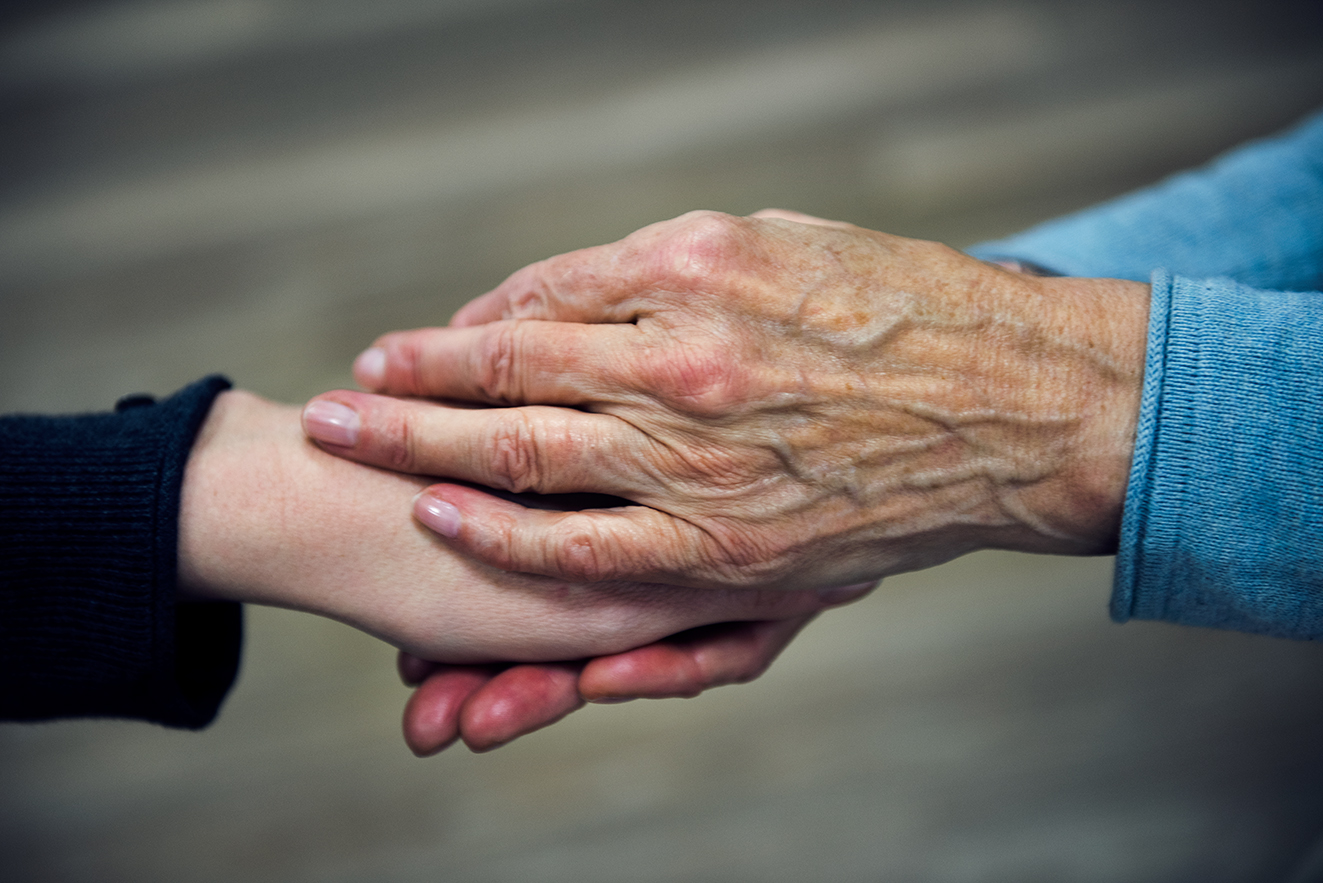 Die Hand einer &auml;lteren Frau h&auml;lt die Hand einer j&uuml;ngeren Frau in einer tr&ouml;stenden Geste.