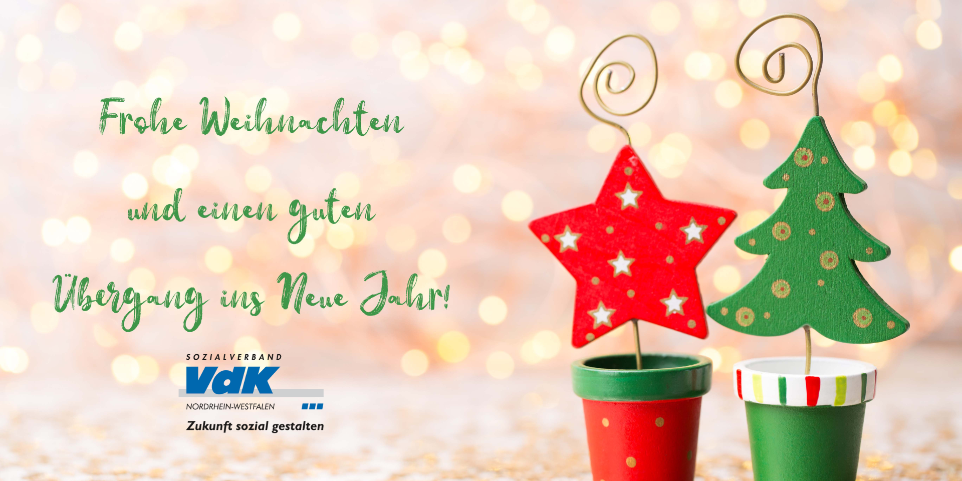 für eine stimmungsvolle (Vor-)Weihnachtszeit Weihnachtsmotiv mit rotem Stern und grünen Tannenbaum aus Holz in kleinen Tontöpfchen. Links davon das VdK-NRW-Logo und grüne Schrift: Frohe Weihnachten und einen guten Übergang ins neue Jahr.
