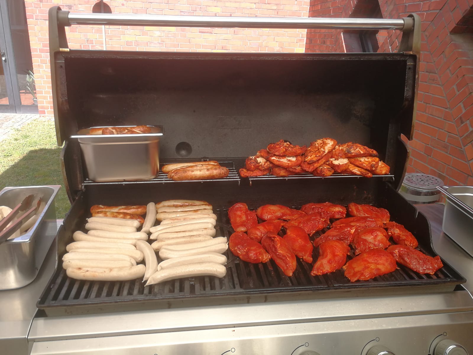 Aufgeklappter, gro&szlig;er Grill mit reichlich W&uuml;rstchen und Grillfleisch