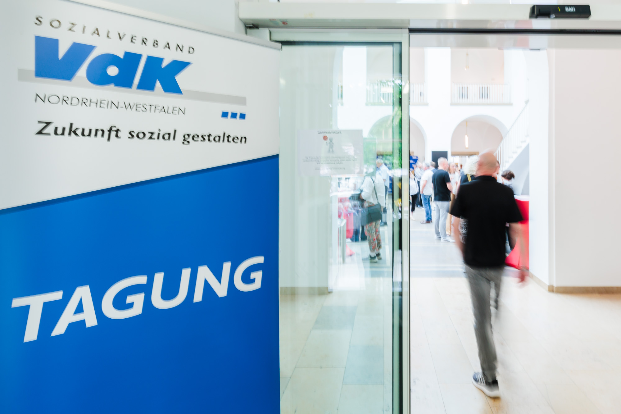 Gläserne Eingangstür zu einem Saal. Links davon ein Banner mit VdK-Logo und der Aufschrift Tagung.