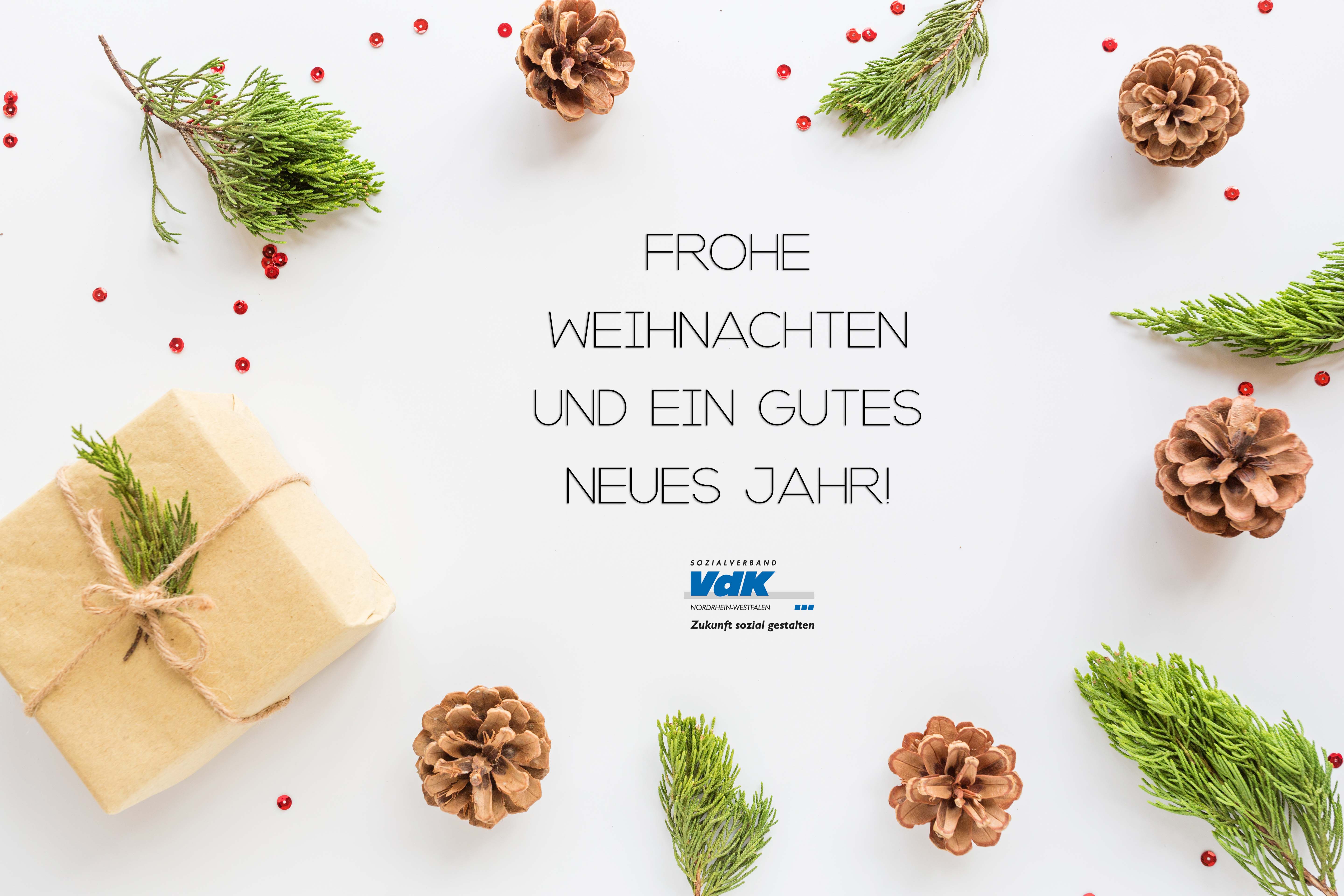 Tannenzapfen, Tannenzweige und ein kleines Packpapierpäckchen sind im Kreis arrangiert um einen Schriftzug: Frohe Weihnachten und ein gesundes neues Jahr. Darunter das Logo des VdK NRW