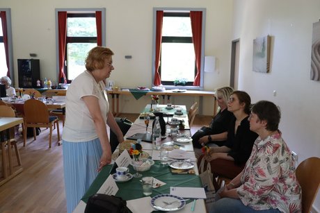 Treffen der Vertreterinnen der Frauen. Eine Frau steht und spricht mit drei Frauen, die am Tisch sitzen.