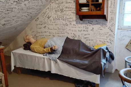 Bildausschnitt einer Zelle mit Bett und Puppe