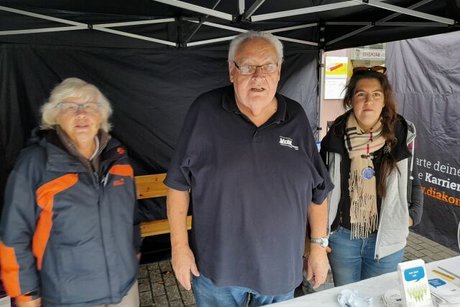 Zwei Frauen und ein Mann stehen im Stand des VdK hinter einem Tisch mit Broschüren.