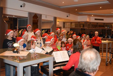 Ein Kinderchor mit roten Weihnachtsmützen singen lustige Weihnachtslieder