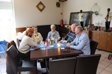 Frühlingsfest Fünf Personen sitzen an einem Tisch und unterhalten sich miteinander.