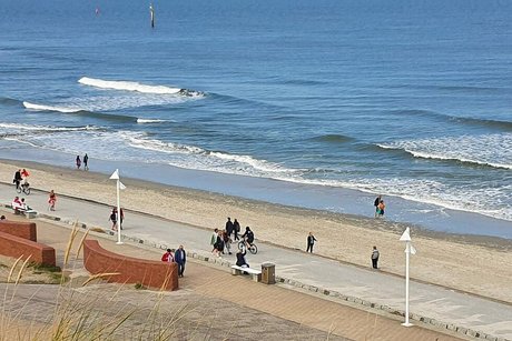 Blick aus den Dünen hinunter zum Strand und auf die asphaltierte Strandpromenade.