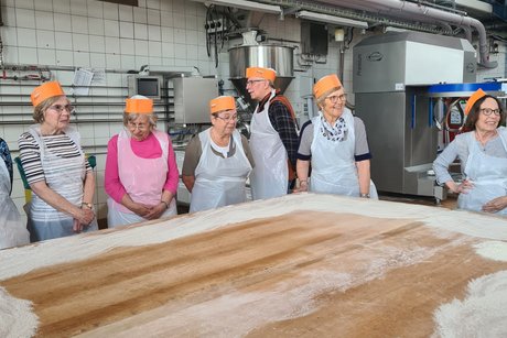 Besuch bei Bäckerei Peter. Mehrere Personen stehen an einem Tisch zum Teig kneten.