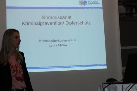 Eine Frau steht vor einer Leinwand.