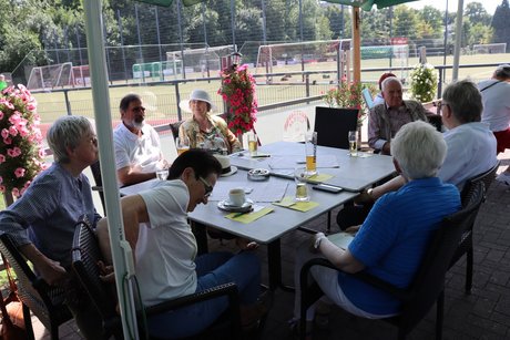Mehrere Menschen sitzen an Tischen im Biergarten.