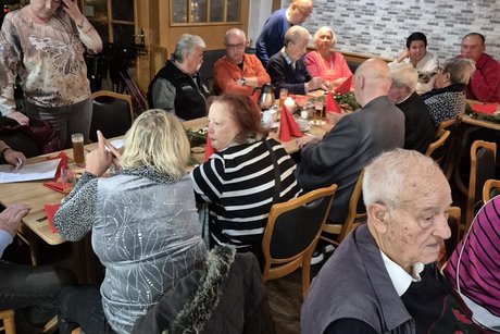 Jahresabschlussfeier mehere Meschen sitzen beisammen.