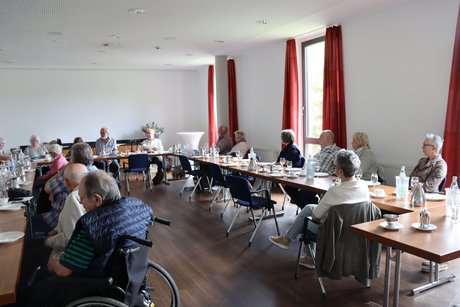 Jahreshauptversammlung 2026 Die Mitglieder des VdK Ortsverband sitzen an langen Tischen und hören dem Vorsitzenden zu.