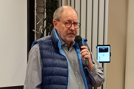 Auf dem Bild sieht man den Vorsitzenden des VdK OV Bilk, Man sieht einen &auml;lteren Herren mit Brille und blauer Weste mit einem Mikrofon in der Hand.
