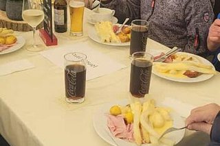 Menschen sitzen gemeinsam in einem Saal und essen Spargel mit Kochschinken und anderen Beilagen.