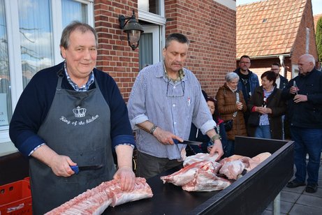 Zwei Fleischer stehen an einem Tisch und zerlegen ein Schwein