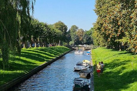 Blick auf die Gracht, an dessen Ufer einige kleine Boote vertäut sind.