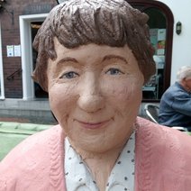 Die Skulptur Alltagsmensch in Straelen ist eine Frau mit braunem Haar, rosa Jacke und Bluse mit Punkten.