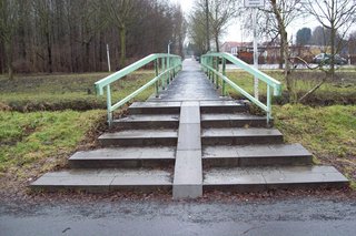 Eine Fußgängerbrücke deren Treppenstufen durch eine schmale Schrägfläche geteilt werden.