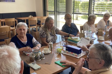 Meenschen sitzen an einem langen Tisch und spielen Bingo.
