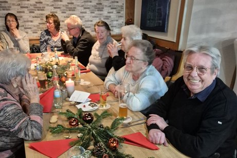 Jahresabschlussfeier mehere Meschen sitzen beisammen.