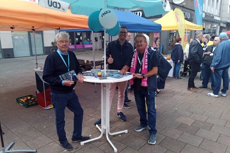 Mehrere Personen stehen an einem Info-Tisch.