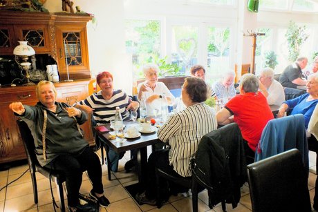 Mehrere Menschen sitzen an gedeckten Tischen.