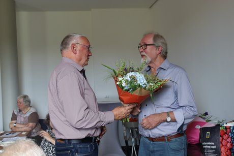 Jahreshauptversammlung 2026 Ein Mann gibt einem anderen Mann einen Blumenstrauß.