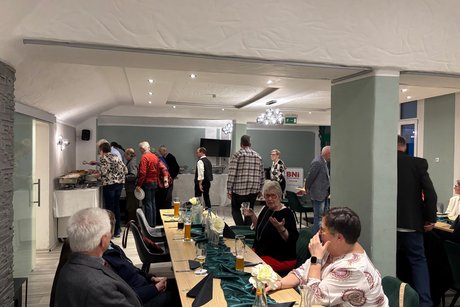 Menschen sitzen an Tischen und unterhalten sich