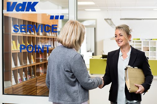 Zwei Frauen begrüßen sich vor einer Tür mit der Aufschrift VdK.