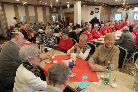 Mehrere Menschen sitzen an langen festlich gedeckten Tischen.
