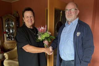 B. Arkenau überreicht S. Engelbrecht einen Blumenstrauß