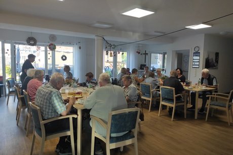 Bewohner und Mitglieder sitzen gemütlich zusammen an der Kaffeetafel