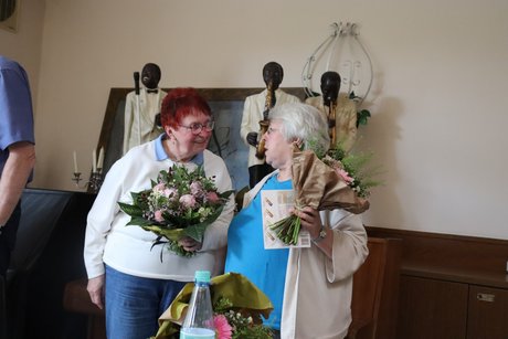 Eine Frau bedankt sich bei einer anderen Frau mit einem Blumenstrau&szlig;.